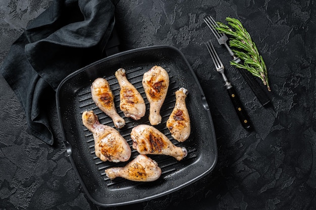 Grilled Chicken leg drumstick with herbs, poultry meat. Black background. Top view.