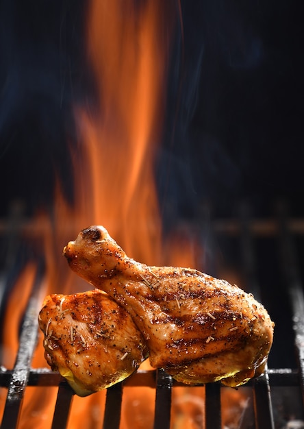 Photo grilled chicken leg on the flaming grill