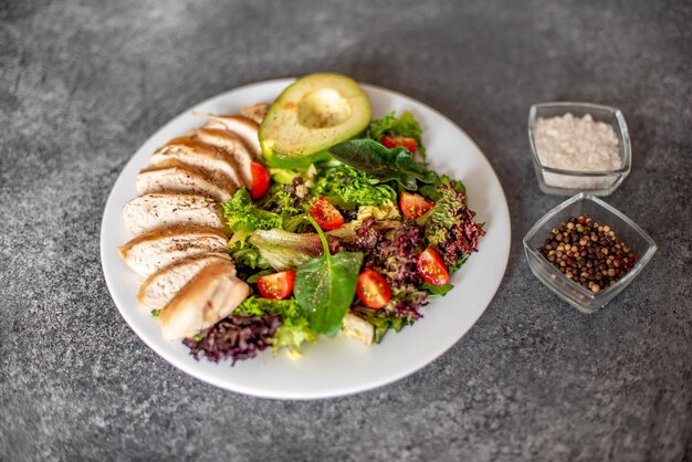 Grilled chicken meat and fresh vegetable salad of tomato avocado lettuce and spinach