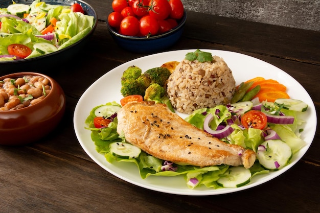 Grilled chicken in a plate with salad and rice isolated wood table background top view photo