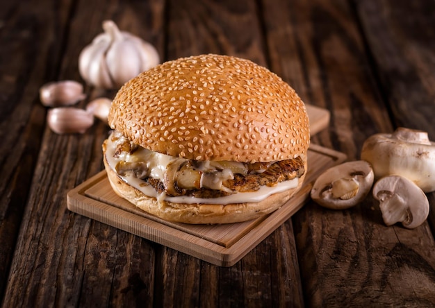 Grilled Chicken Ranch burger isolated on cutting board top view on dark background american fast food