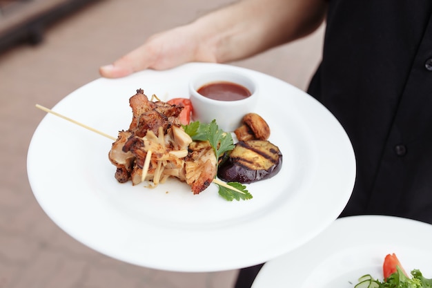 Grilled chicken and salad in the hand of the waiter