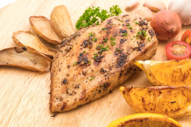 Grilled chicken steaks with vegetables on wood board 