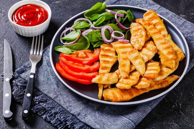 Grilled chicken strips on a plate with vegetables