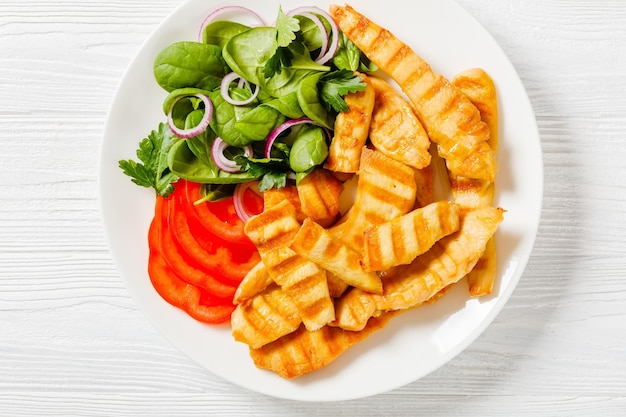 Grilled chicken strips on a plate with vegetables