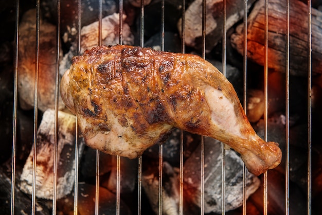 Grilled chicken thigh over flames on a barbecue.