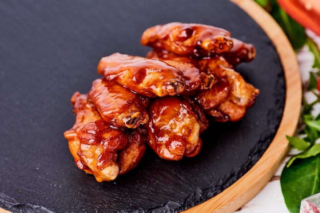 Grilled chicken wings on black stone background.