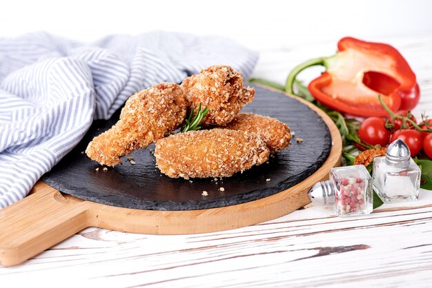 Grilled chicken wings on black stone background.