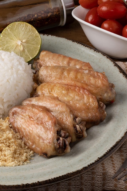 Grilled chicken wings served with rice and toasted manioc flour