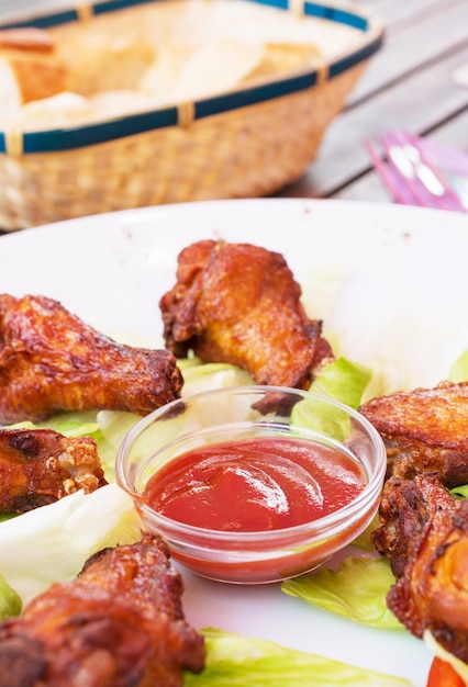 Grilled chicken wings with ketchup and greens