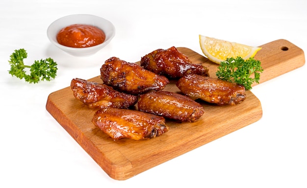 Photo grilled chicken wings with ketchup and sauces on a wooden board traditional baked bbq