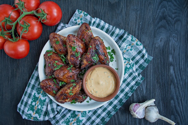 Жареные куриные крылышки с соусом и зеленью.