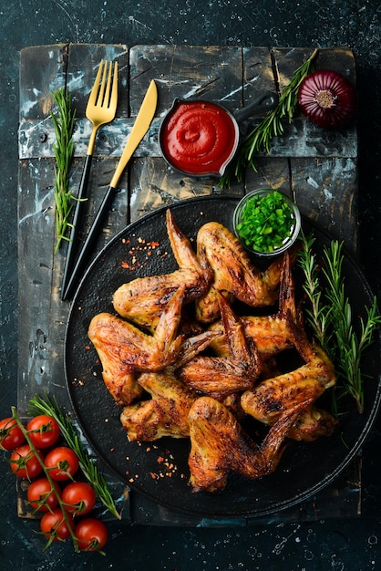 Grilled chicken wings with sauce and spices on a black stone plate Top view Free space for text