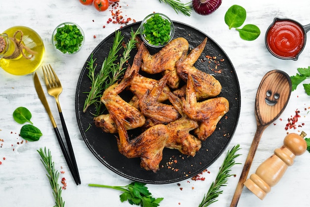 Grilled chicken wings with sauce and spices on a black stone plate Top view Free space for text