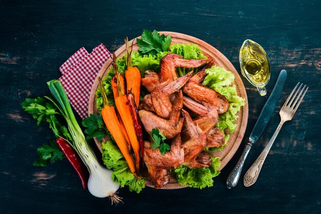 Grilled Chicken Wings with Vegetables and Carrots On a wooden background Top view Copy space