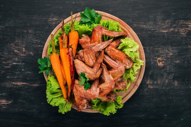 Grilled Chicken Wings with Vegetables and Carrots On a wooden background Top view Copy space