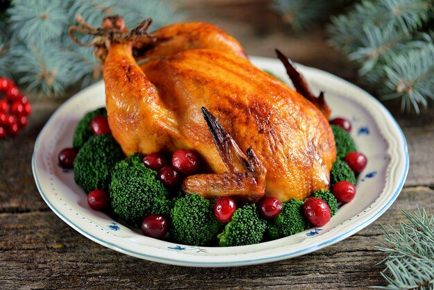 Grilled chicken with boiled broccoli and cranberries on a wooden background. 