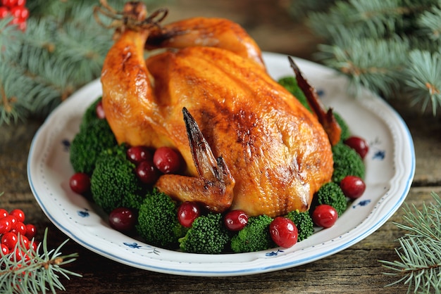 Grilled chicken with boiled broccoli and cranberries on a wooden background. 