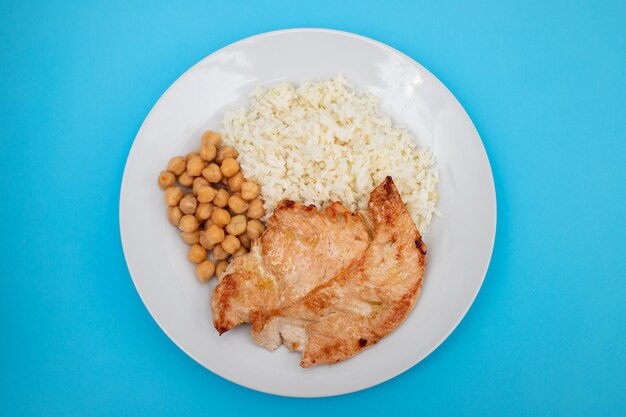 курица-гриль с нутом и отварным рисом в белой тарелке