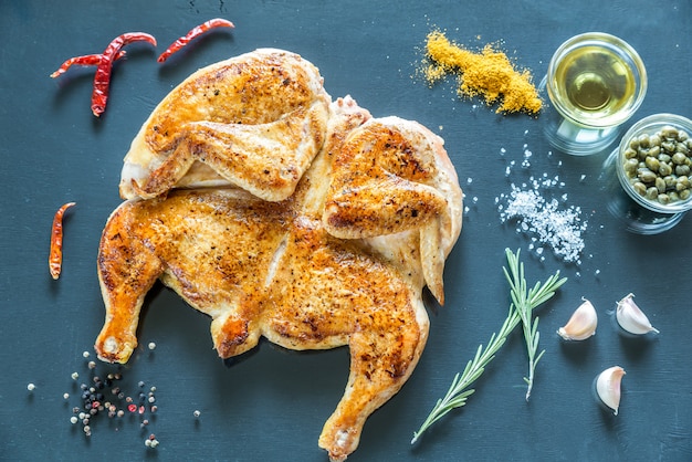 Grilled chicken with ingredients on the dark wooden surface