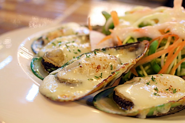 Foto cozze alle vongole alla griglia e formaggio con insalata