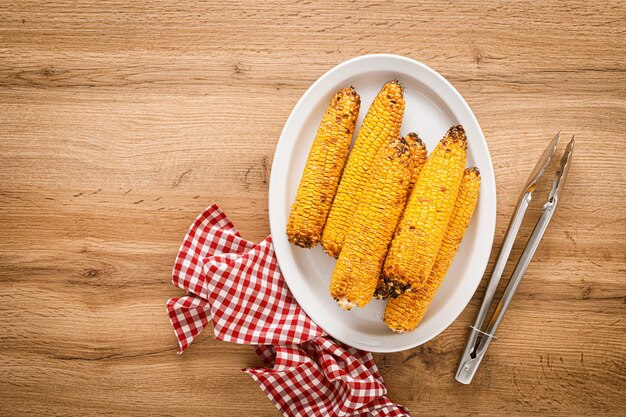 Grilled corn on the cob on wooden table top view