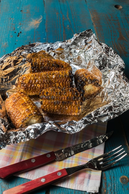 Grilled corn on a foil over old blue wooden table