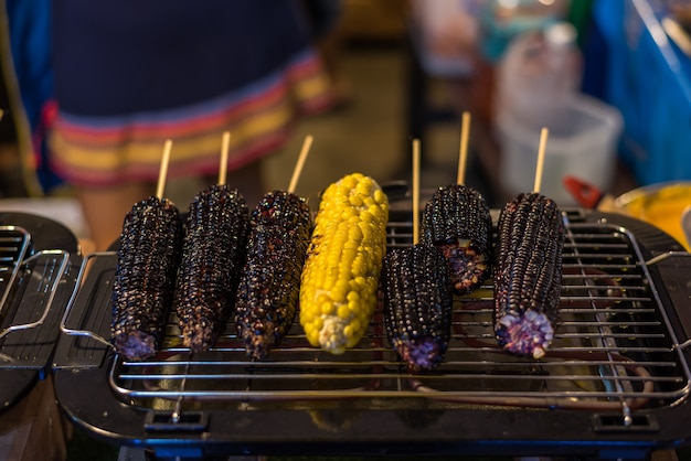 タイの通りの食べ物で焼かれたトウモロコシと紫のトウモロコシ