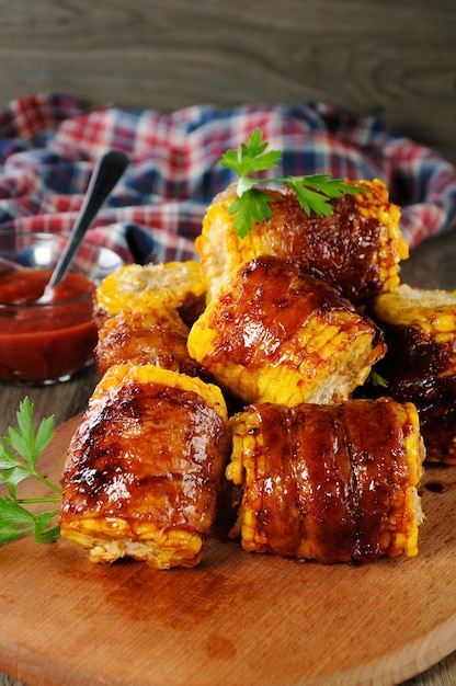Grilled corn wrapped with bacon slices under BBQ sauce