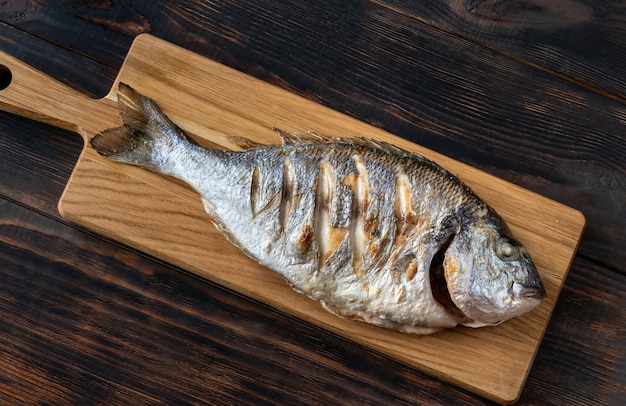 Жареная рыба дорада на деревянной доске