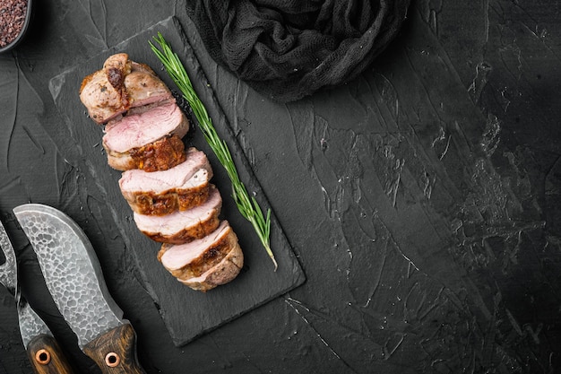 Photo grilled duck meat set, on stone serving board, on black stone background, top view flat lay, with copyspace  and space for text