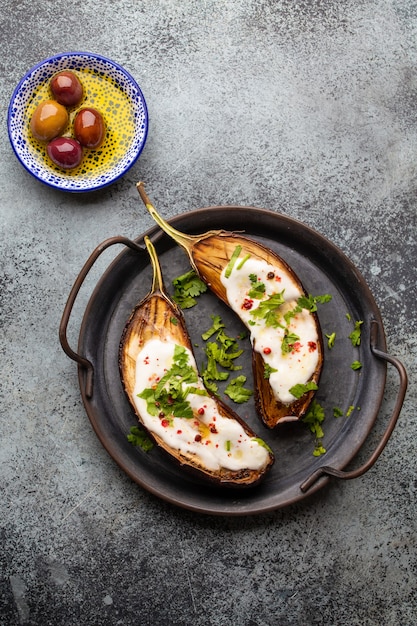 Grilled eggplant served in a pan with yoghurt, fresh cilantro and seasonings. Middle eastern and Mediterranean vegetable meal or appetizer, light and healthy food, top view