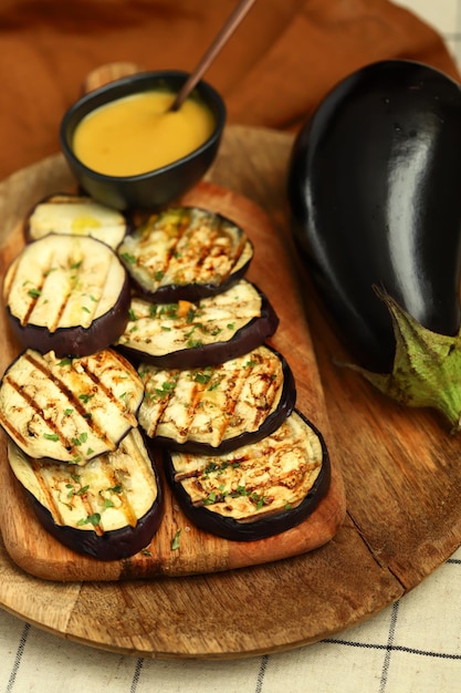Grilled eggplant on a wooden board with honey mustard sauce
