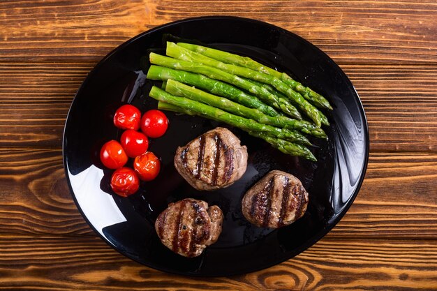 Grilled filet mignon with asparagus and tomatoes Beef sreak on rustic background