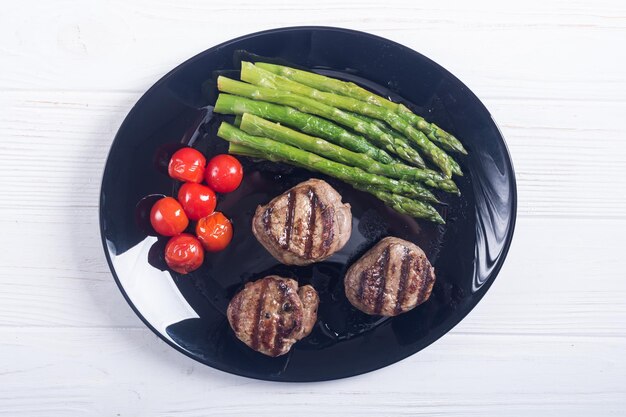 Grilled filet mignon with asparagus and tomatoes Beef sreak on rustic background