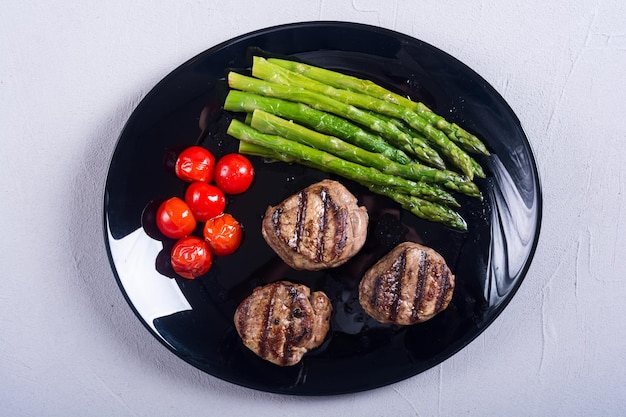 Grilled filet mignon with asparagus and tomatoes Beef sreak on rustic background