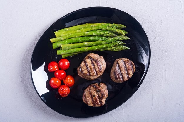 Grilled filet mignon with asparagus and tomatoes Beef sreak on rustic background