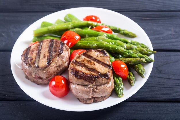 Grilled filet mignon with asparagus and tomatoes beef sreak on rustic background