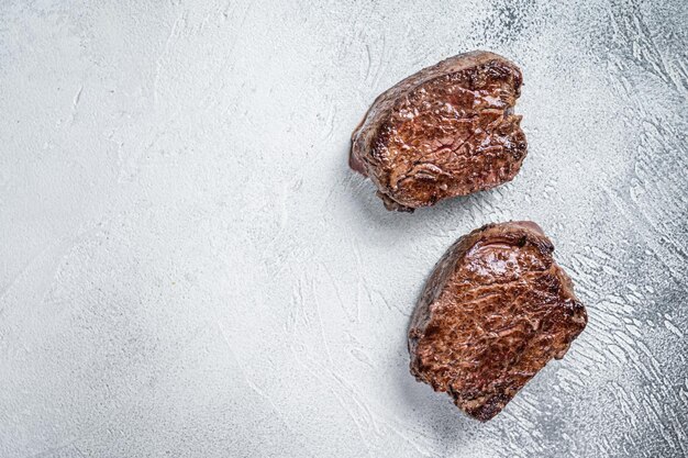 Grilled fillet mignon or tenderloin beef steak on kitchen table. White background. Top view. Copy space.