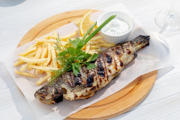 Grilled fish garnished with herbs and fries