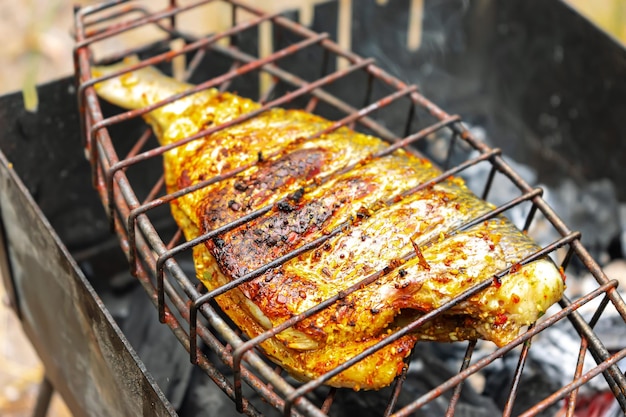 Grilled fish on the grill cooked on fire barbecue