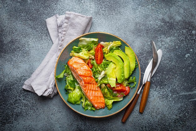 Grilled fish salmon steak and vegetables salad with avocado