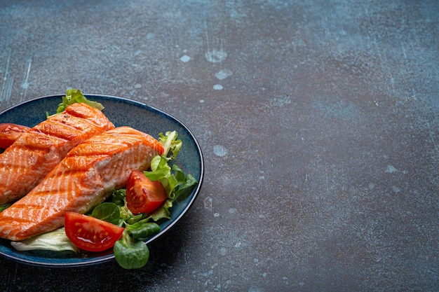 Стейк рыбы-лосося на гриле с овощным салатом на керамике