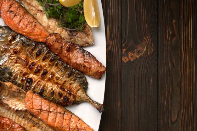 Grilled fish on a white plate with herbs and lemon