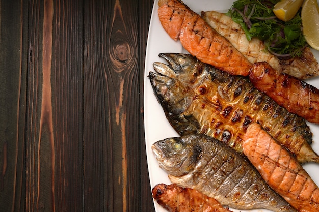 Grilled fish on a white plate with herbs and lemon