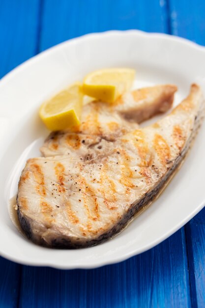 Grilled fish with lemon on wooden table