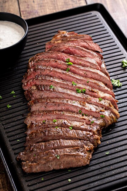 Grilled flank steak with horseradish sauce on a grill pan