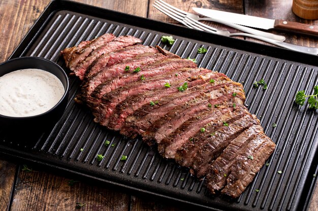 Photo grilled flank steak with horseradish sauce on a grill pan