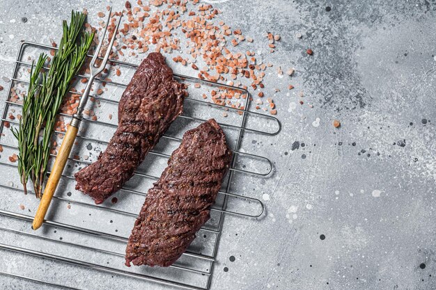 Grilled Flap steak flank cut and Machete skirt steak on grill with herbs Gray background Top view Copy space