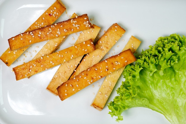 Grilled fried tofu on a plate with sesame and greens